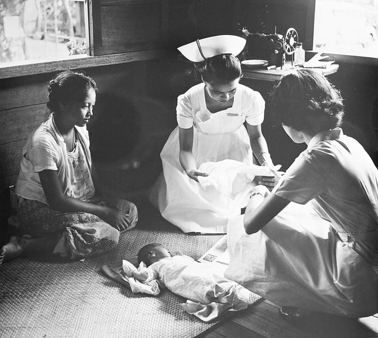 Student-nurse Paz Basconcillo (middle) shows Maxima Madreniko (left), a 17-year-old mother from Quezon City, how to care for her week-old son. Basconcillo is being trained by public health nurse Zenaida Panlilio (right) who helped her deliver the baby at Madreniko’s home.